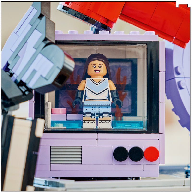 Olivia Rodrigo minifigure in a cheerleader outfit standing inside the TV screen of the LEGO Secret Storage set
