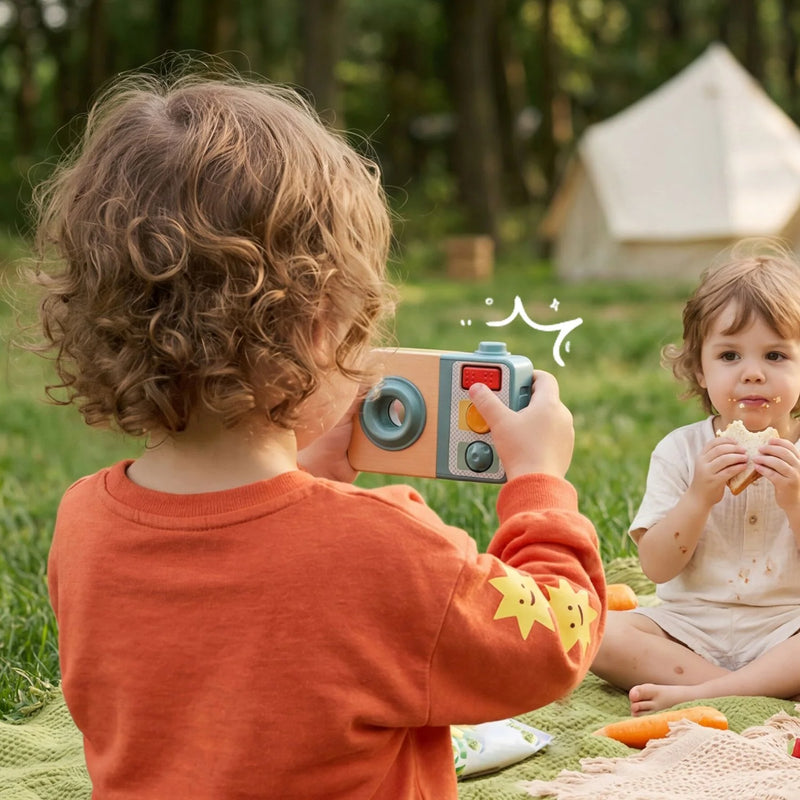 Child looking through the Busy Camera during pretend photography at an outdoor picnic