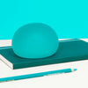 Speks Gump Jumbo Sea Glass stress ball resting on a teal notebook with pencils
