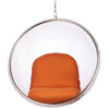 A modern hanging bubble chair with a clear plastic or acrylic spherical outer shell, a silver metal frame, and an orange upholstered seat cushion, suspended by a chain against a white background.