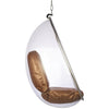 A modern teardrop-shaped hanging egg chair with a transparent clear plastic shell, a metallic silver frame, and a brown cushioned seat and backrest, suspended by a chain against a white background.