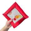 Red Sensory Touch and Search Bag held in one hand with hidden shapes visible