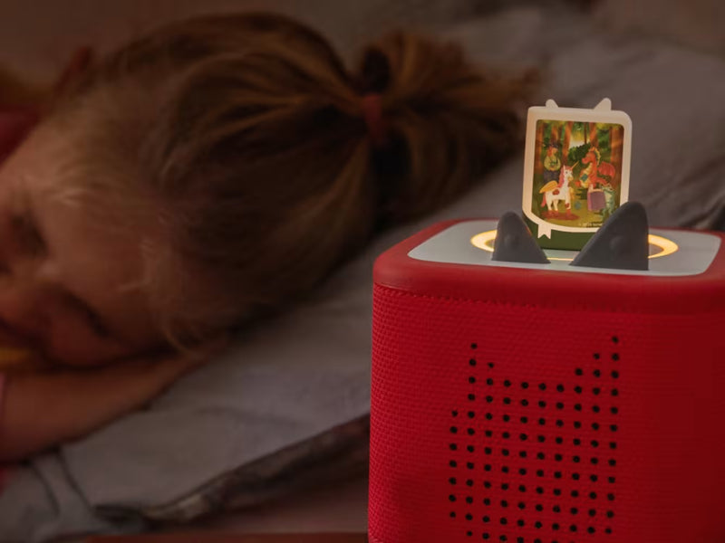 Enchanted Bedtime Stories Book Tonie on a red Toniebox beside a child resting in bed