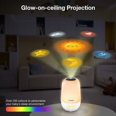 A Vtech glow-on-ceiling projection night light shown in a dim nursery setting, projecting colorful celestial designs like a sun, moon, stars, and planets onto the wall. Text highlights glow-on-ceiling projection and customizable colors.